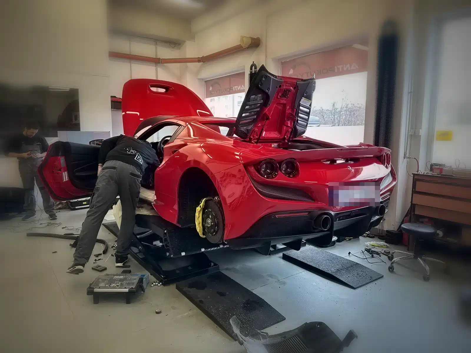 Ferrari sobre elevador en taller durante la instalación de un RADAGO